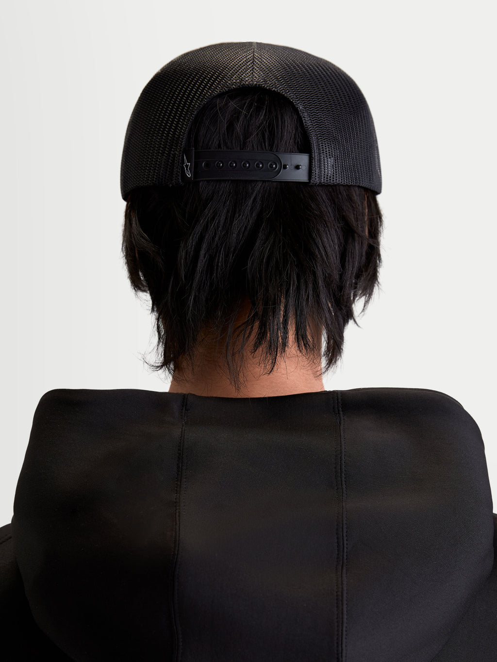 Alpinestars Gravel Trucker pet, sportswear snapback-pet, unisex, zwart, achteraanzicht op model met ademende poly-mesh achterkant en verstelbare snapback-sluiting