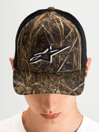 Alpinestars Thicket Realtree Trucker pet, sportswear trucker pet gedragen door een model, Realtree-camouflage en zwart, gebogen klep, gestructureerd kroon en wit geborduurd Astars-logo op de voorkant