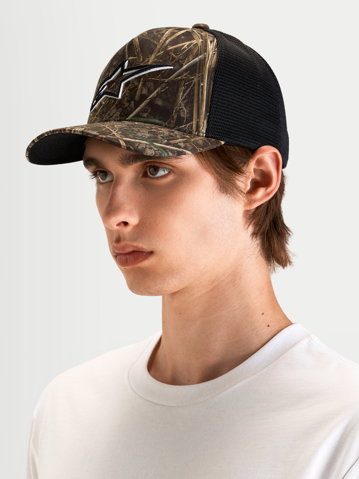 Alpinestars Thicket Realtree Trucker pet, sportswear trucker pet in Realtree camo en zwart, met gebogen klep, gestructureerde kroon en 3D geborduurd Astars-logo, gedragen door een model