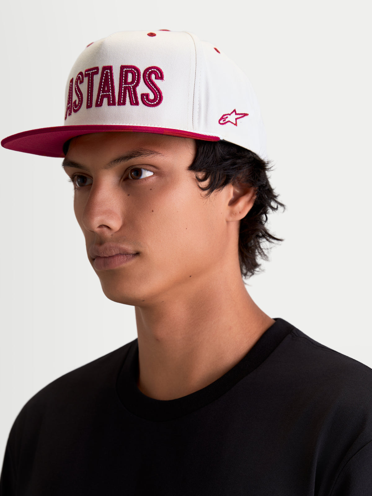 Alpinestars Stadium Snapback pet, sportswear lifestyle-pet, gebroken wit en rood, voorzien van een platte klep, gestructureerde kroon en Astars-logoapplicatie met contrasterend stiksel en zijborduursel, modeloverzicht.