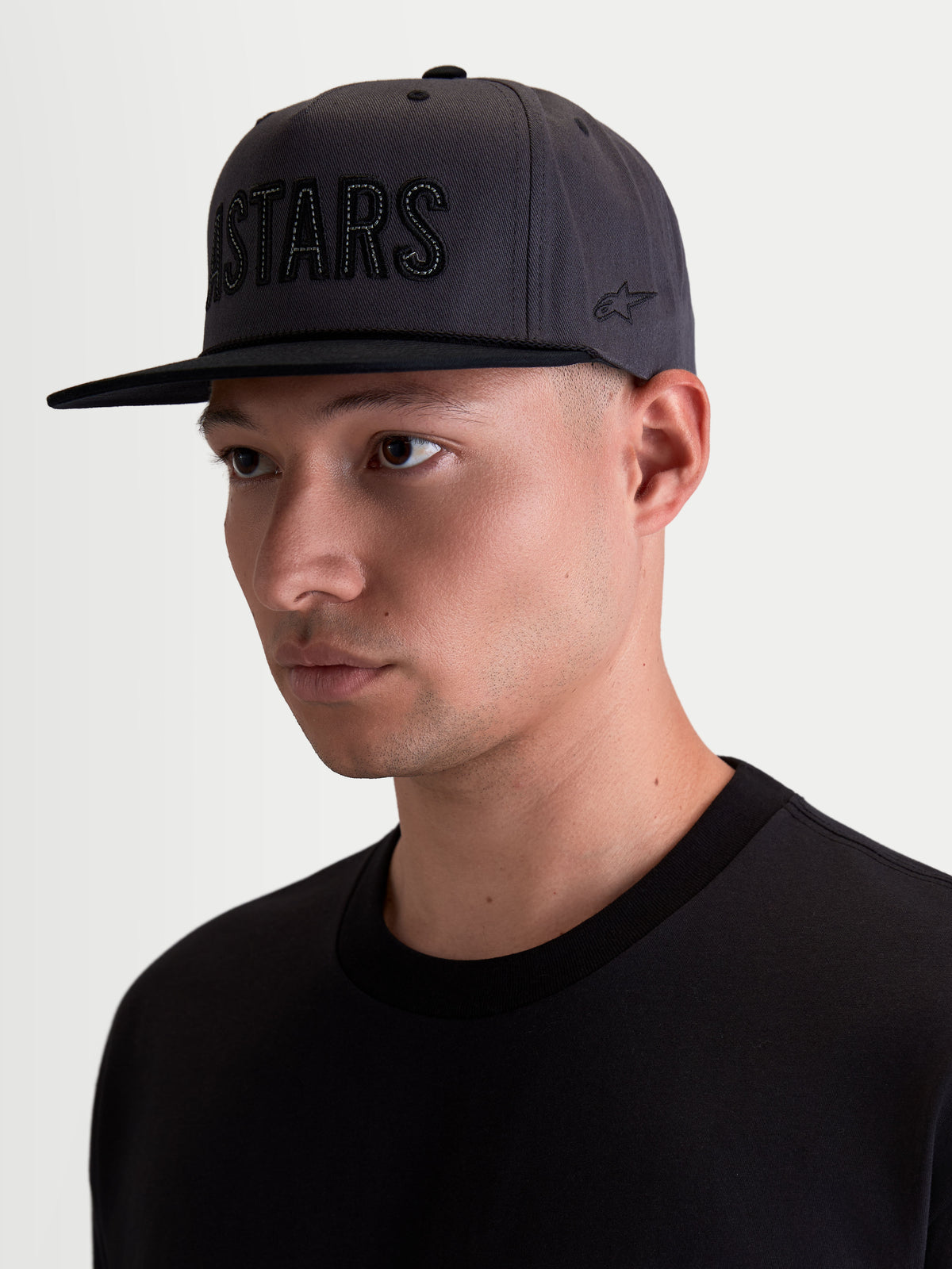 Alpinestars Stadium Snapback Pet, motorsport-geïnspireerde sportswearpet voor heren, donkergrijs en zwart, gestructureerde kroon met platte klep, Astars-logoapplicatie op de voorzijde en geborduurd logo op de zijkant, gemaakt van katoenen keperstof, on-model weergave