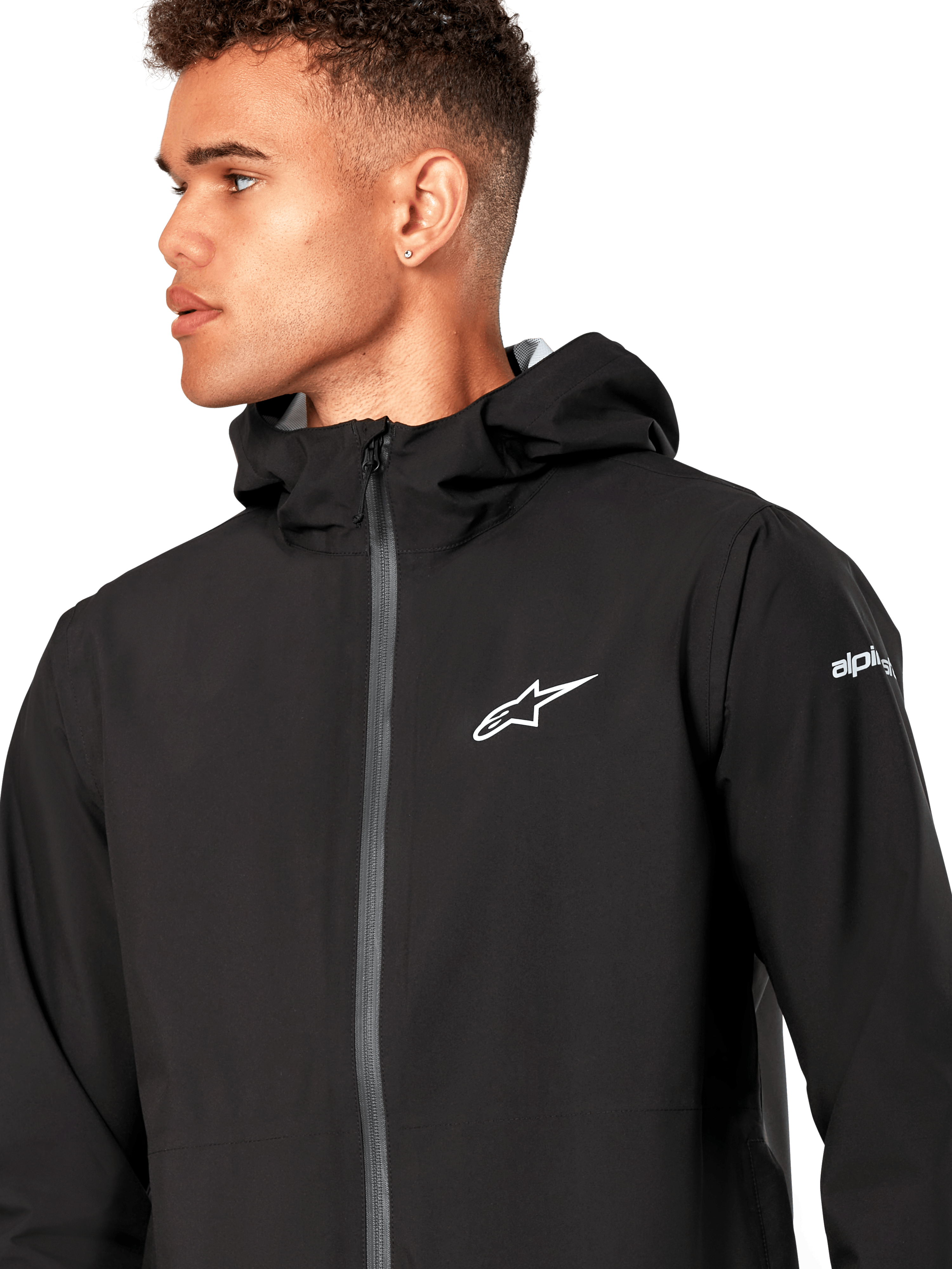 Alpinestars Kascade regenjas, zwarte shell regenjas, met een wit sterlogo op de borst, vaste capuchon en gecoate omgekeerde spiraalrits aan de voorkant, casual op motorsport geïnspireerde performance-bovenkleding