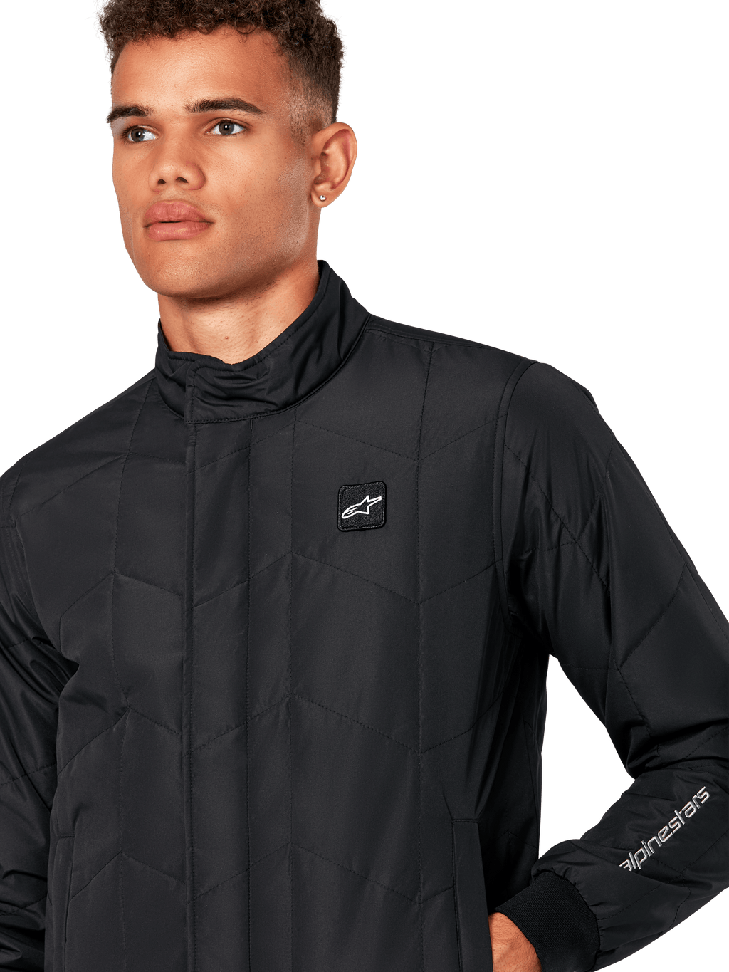 Alpinestars Precedent jas, gestept sportjack voor heren in het zwart, close-up van de lage kraag, logopatch op de borst en het borduursel op de mouw, met een iconisch schuin gestikt patroon voor een op de motorsport geïnspireerde look.