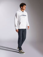Alpinestars Blaze V3 Hoodie, White and Navy, casual streetwear worn by a model with dark blue jeans and sneakers, features a drawstring hood and bold front logo print, modern motorsport-inspired design