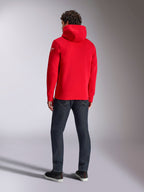 Alpinestars Linear Wordmark V3 Hoodie, casual red pullover hoodie, back view featuring the hood and white Ageless logo on the sleeve, paired with dark blue jeans and black shoes, lifestyle motorsport streetwear