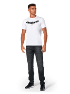 Alpinestars Elliptic CSF Tee, T-shirt met korte mouwen, wit, zwart gebogen Astars-logo met oranje stersymbool, gedragen door model met zwarte jeans en sneakers, casual motorsport streetwear