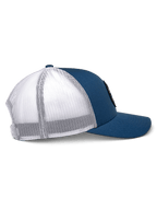 Alpinestars Gambit Trucker Pet, blauw en wit, zijaanzicht, gebogen klep met gestructureerde kroon, blauwe twill voorpanelen en witte mesh achterkant, casual motorsport-geïnspireerde hoofdbedekking
