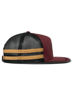 Alpinestars Backline Trucker pet, Brick, zwart en mosterdgeel, zijaanzicht, donkerrode twill voorkant met zwarte mesh achterkant en gele zijstrepen, platte klep met zwarte suttache-afwerking, casual motorsport-geïnspireerde hoofdbedekking