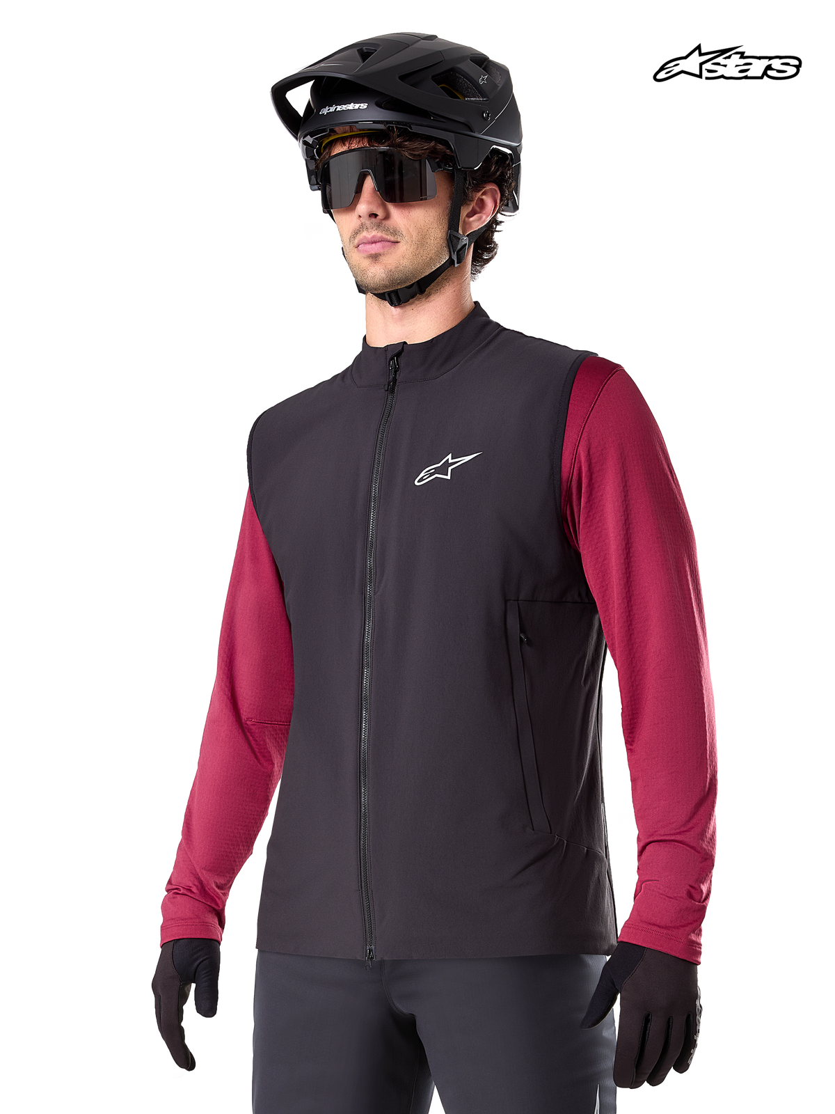 Alpinestars A-Dura Thermal vest, heren mountainbike thermisch vest in zwart, gedragen door model met helm en rode trui met lange mouwen, isolatie voor koud weer MTB-rijden