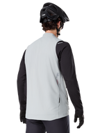 Alpinestars A-Dura Thermisch Vest, Titanium Grijs, achteraanzicht van model met zwart jersey met lange mouwen en MTB-helm, minimalistisch ontwerp met klein rood sterlogo op de rug, lichtgewicht geïsoleerde fietsgilet voor off-road rijden
