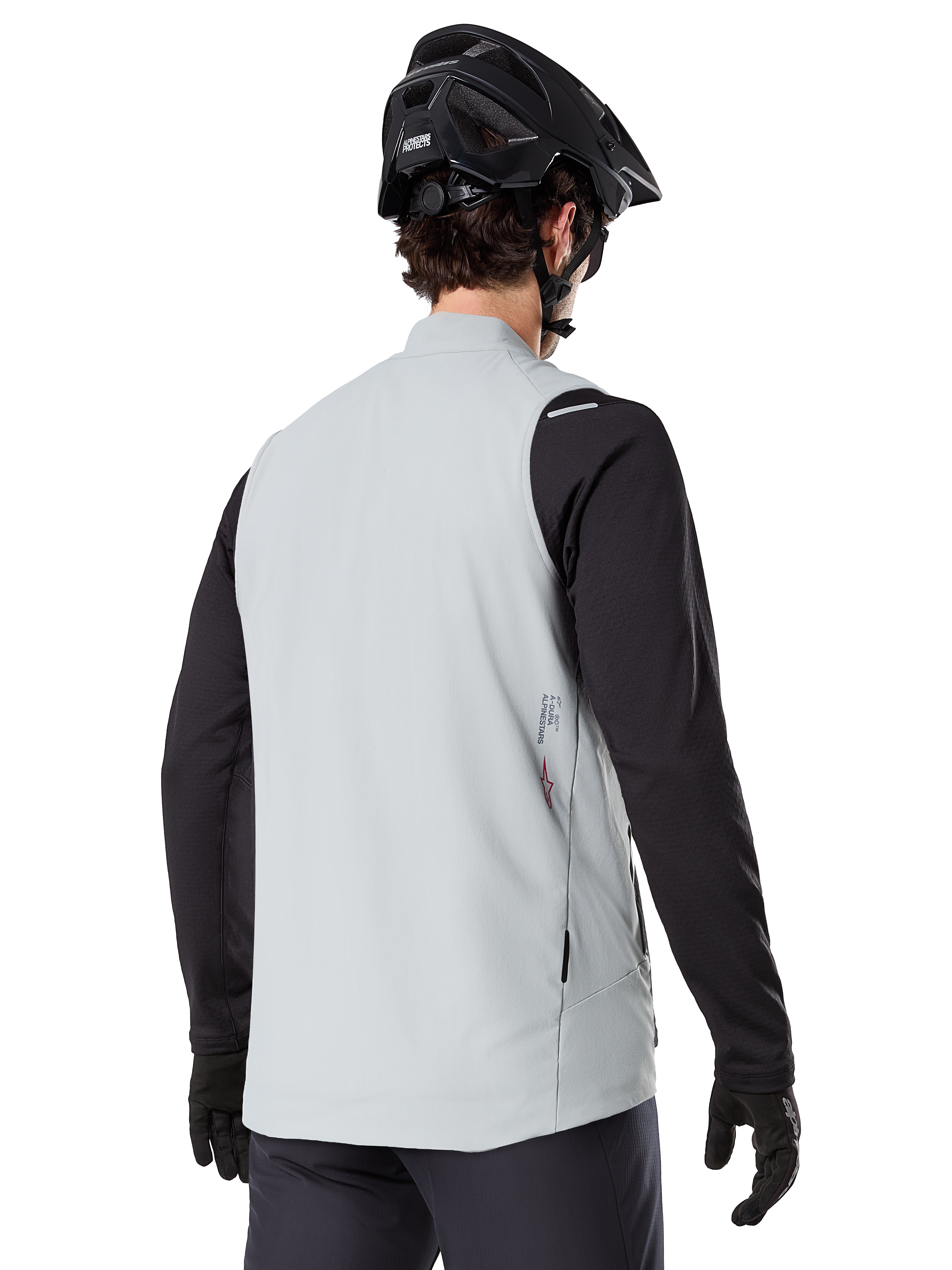 Alpinestars A-Dura Thermisch Vest, Titanium Grijs, achteraanzicht van model met zwart jersey met lange mouwen en MTB-helm, minimalistisch ontwerp met klein rood sterlogo op de rug, lichtgewicht geïsoleerde fietsgilet voor off-road rijden
