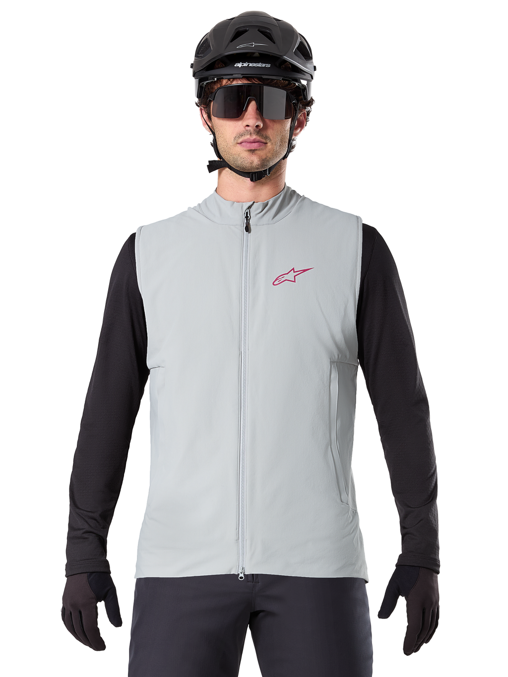Alpinestars A-Dura Thermal Vest, fietsbodywarmer, Titanium grijs, gedragen met een zwarte jersey met lange mouwen en zwarte fietshelm, rood Alpinestars ster-logo op de borst, lichtgewicht en geïsoleerd voor mountainbiken.