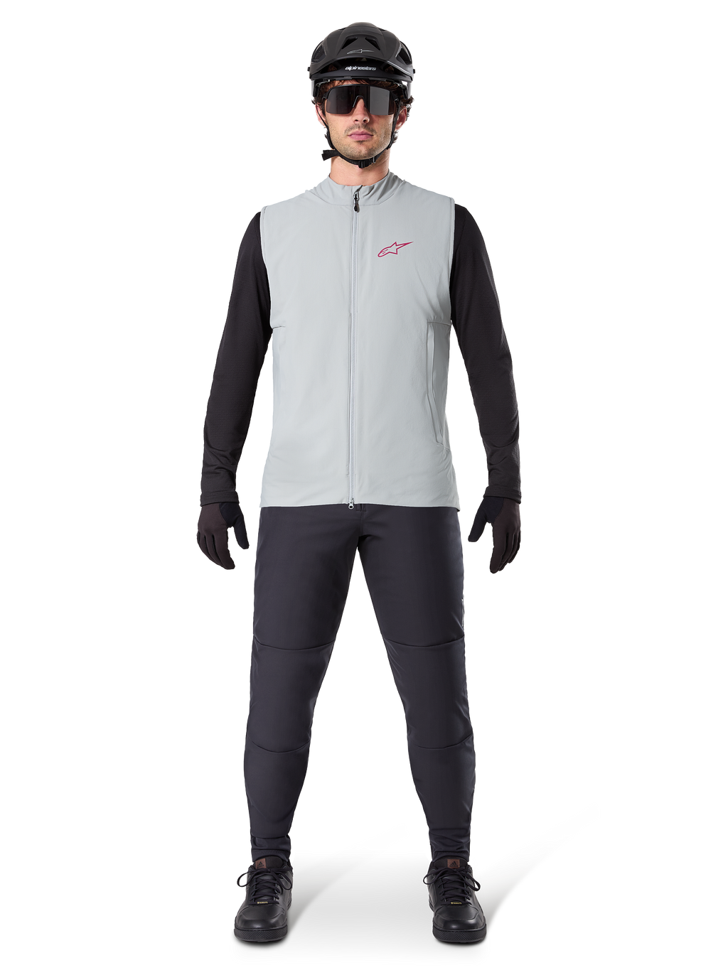 Alpinestars A-Dura Thermal Vest, fietsvest, Titanium grijs, gedragen met zwarte jersey met lange mouwen en zwarte broek, zwarte helm en zonnebril, voorzien van een rood Alpinestars-logo, lichtgewicht thermische isolatie voor mountainbiken