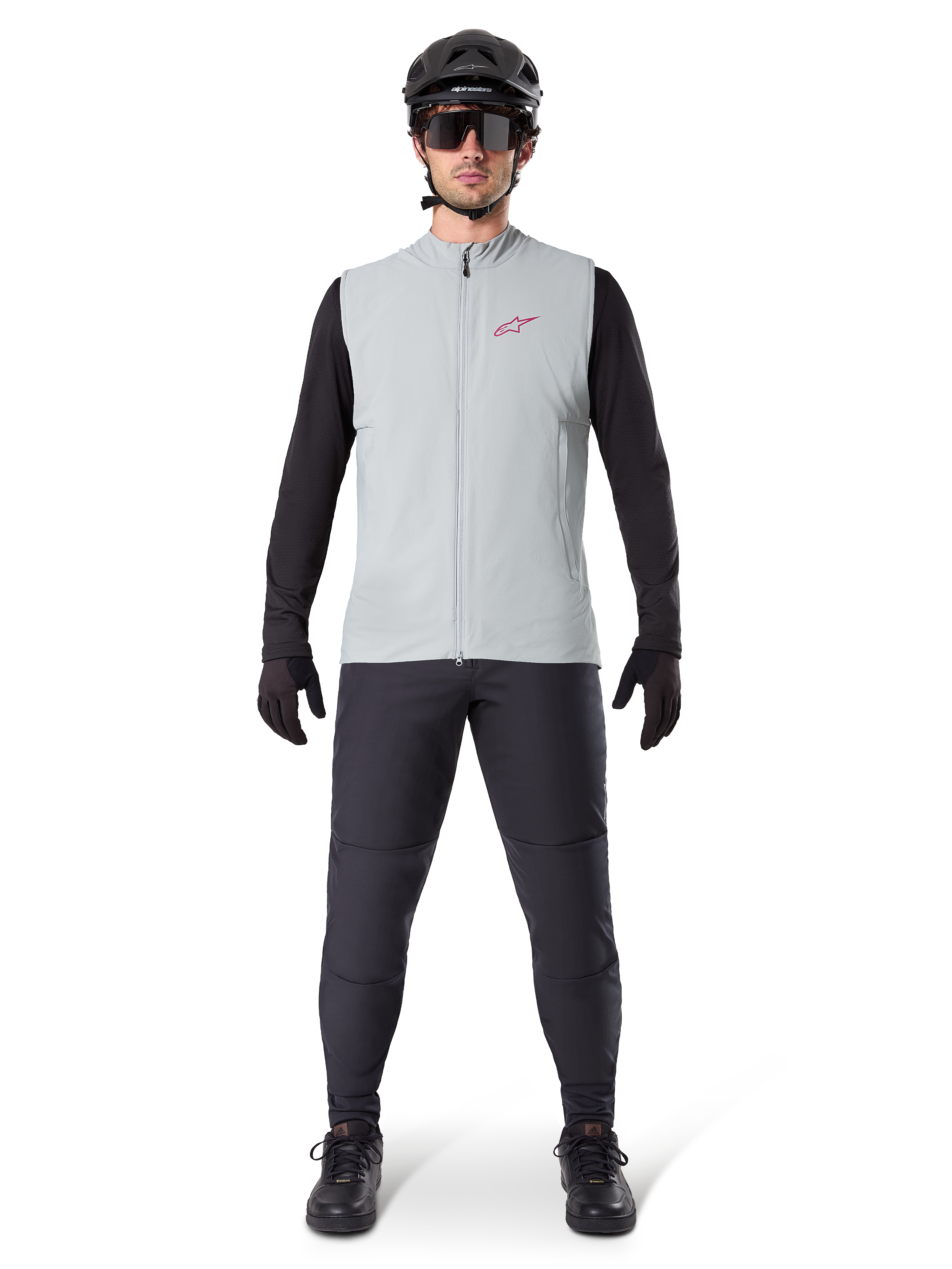 Alpinestars A-Dura Thermal Vest, fietsvest, Titanium grijs, gedragen met zwarte jersey met lange mouwen en zwarte broek, zwarte helm en zonnebril, voorzien van een rood Alpinestars-logo, lichtgewicht thermische isolatie voor mountainbiken