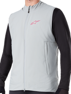 Alpinestars A-Dura Thermal Vest, titanium grijs geïsoleerd fietsvest, voorzien van een roze sterlogo op de borst, gedragen over een zwarte top met lange mouwen, inclusief een verticale zak met ritssluiting en volledige rits aan de voorzijde, ontworpen voor mountainbiken in koud weer.