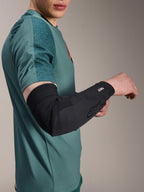 Alpinestars A-Motion Plasma elleboogmouw, fiets elleboogbeschermer, zwart, gedragen door een rijder met een groenblauw shirt, voorzien van Alpinestars-logo en Nucleon Plasma-branding, slank en ademend ontwerp voor MTB-bescherming