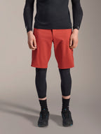 Alpinestars A-Motion Plasma Knee Sleeve, zwarte MTB kniebeschermer, gedragen met rode shorts en zwart shirt met lange mouwen, slank ergonomisch ontwerp, lichtgewicht mesh-constructie voor off-road rijden