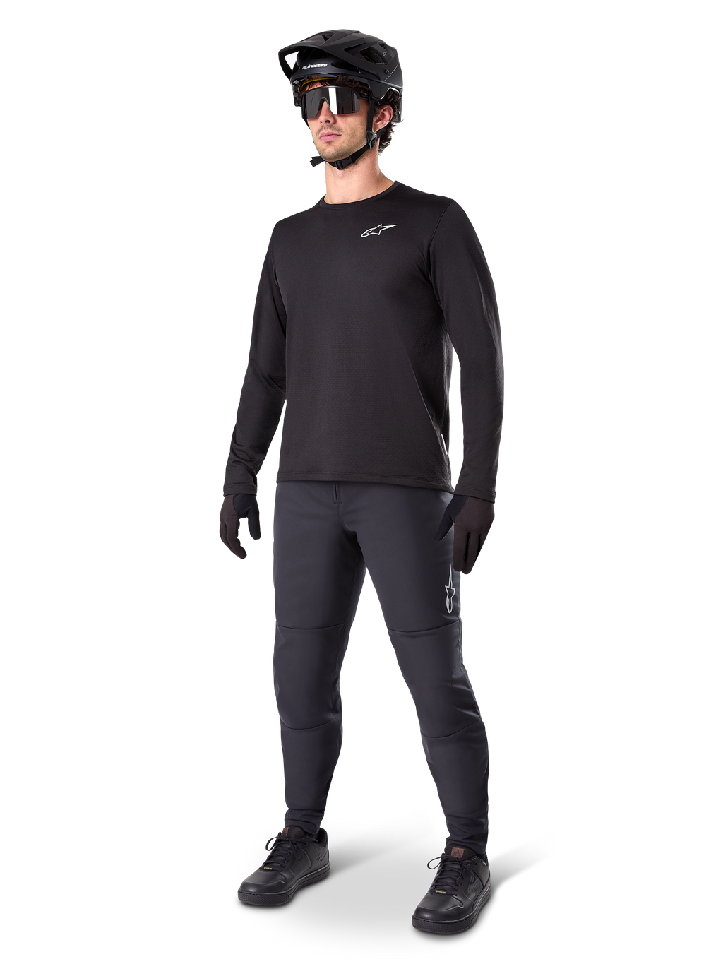 Mountainbiker in Alpinestars A-Dura Thermal Pants, zwart, gecombineerd met een zwarte jersey met lange mouwen, zwarte helm en zonnebril, met een zilveren Alpinestars-logo op het linkerdijbeen, ontworpen voor trailritten in koud weer