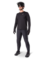 Mountainbiker in Alpinestars A-Dura Thermal Pants, zwart, gecombineerd met een zwarte jersey met lange mouwen, zwarte helm en zonnebril, met een zilveren Alpinestars-logo op het linkerdijbeen, ontworpen voor trailritten in koud weer