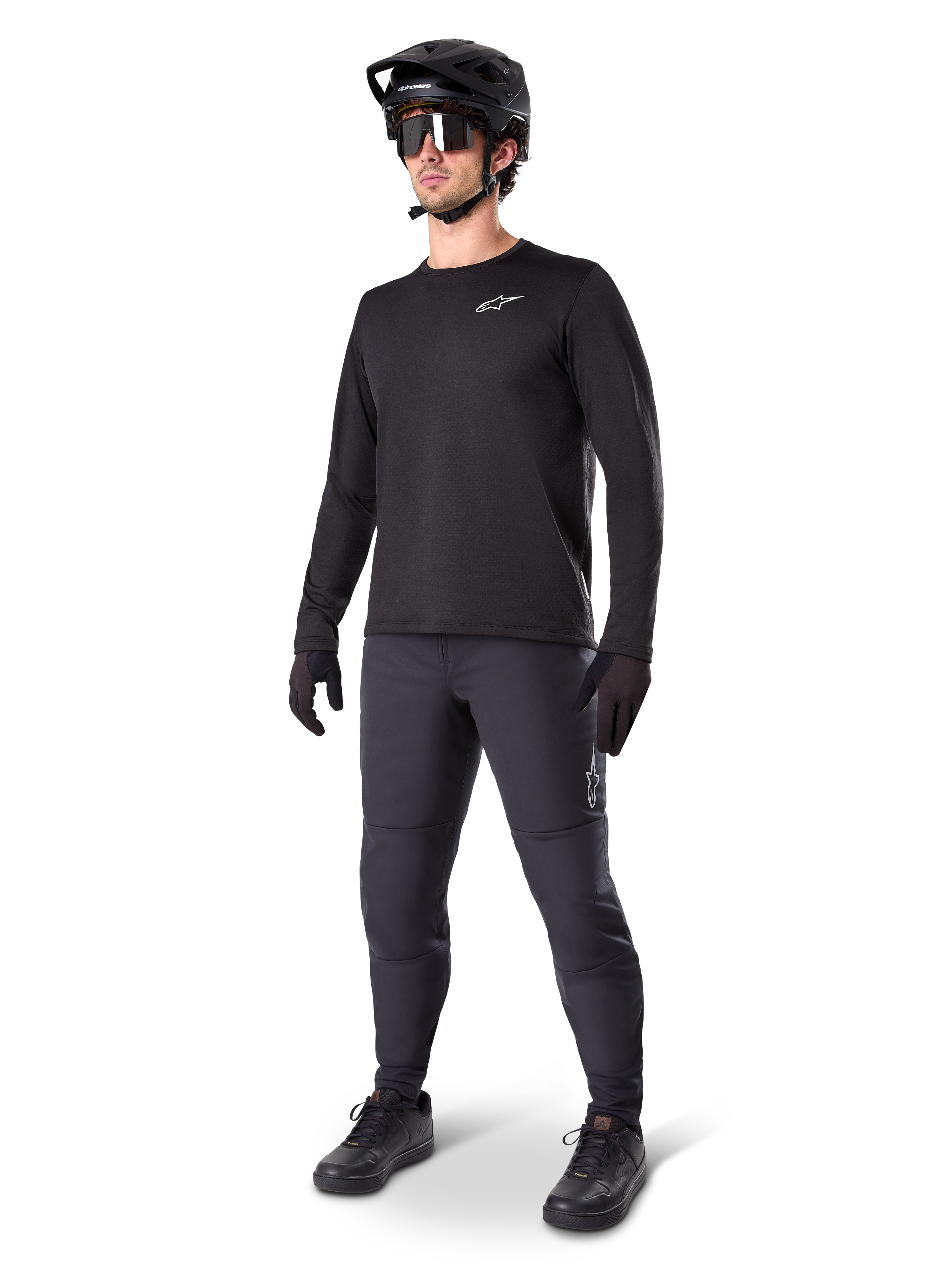Mountainbiker in Alpinestars A-Dura Thermal Pants, zwart, gecombineerd met een zwarte jersey met lange mouwen, zwarte helm en zonnebril, met een zilveren Alpinestars-logo op het linkerdijbeen, ontworpen voor trailritten in koud weer