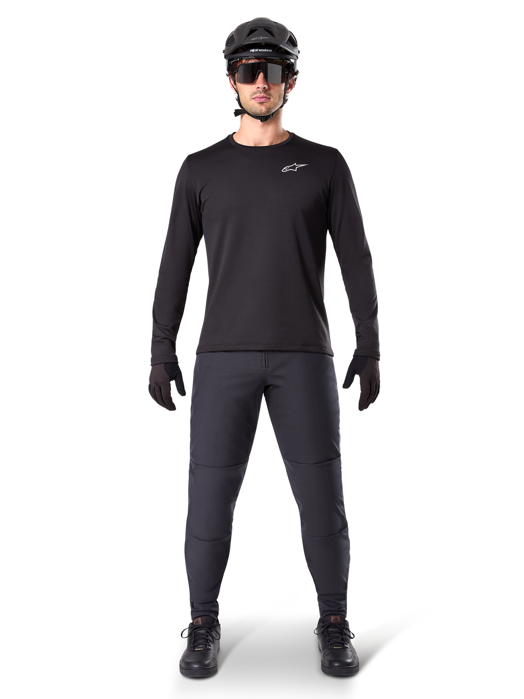Alpinestars A-Dura Thermal Pant, zwarte MTB-broek, gedragen door een rijder in complete mountainbike-uitrusting inclusief een zwart jersey met lange mouwen, helm en zonnebril, duurzame broek met een normale pasvorm voor trailrijden in koud weer