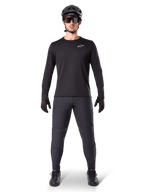 Alpinestars A-Dura Thermal Pant, zwarte MTB-broek, gedragen door een rijder in complete mountainbike-uitrusting inclusief een zwart jersey met lange mouwen, helm en zonnebril, duurzame broek met een normale pasvorm voor trailrijden in koud weer