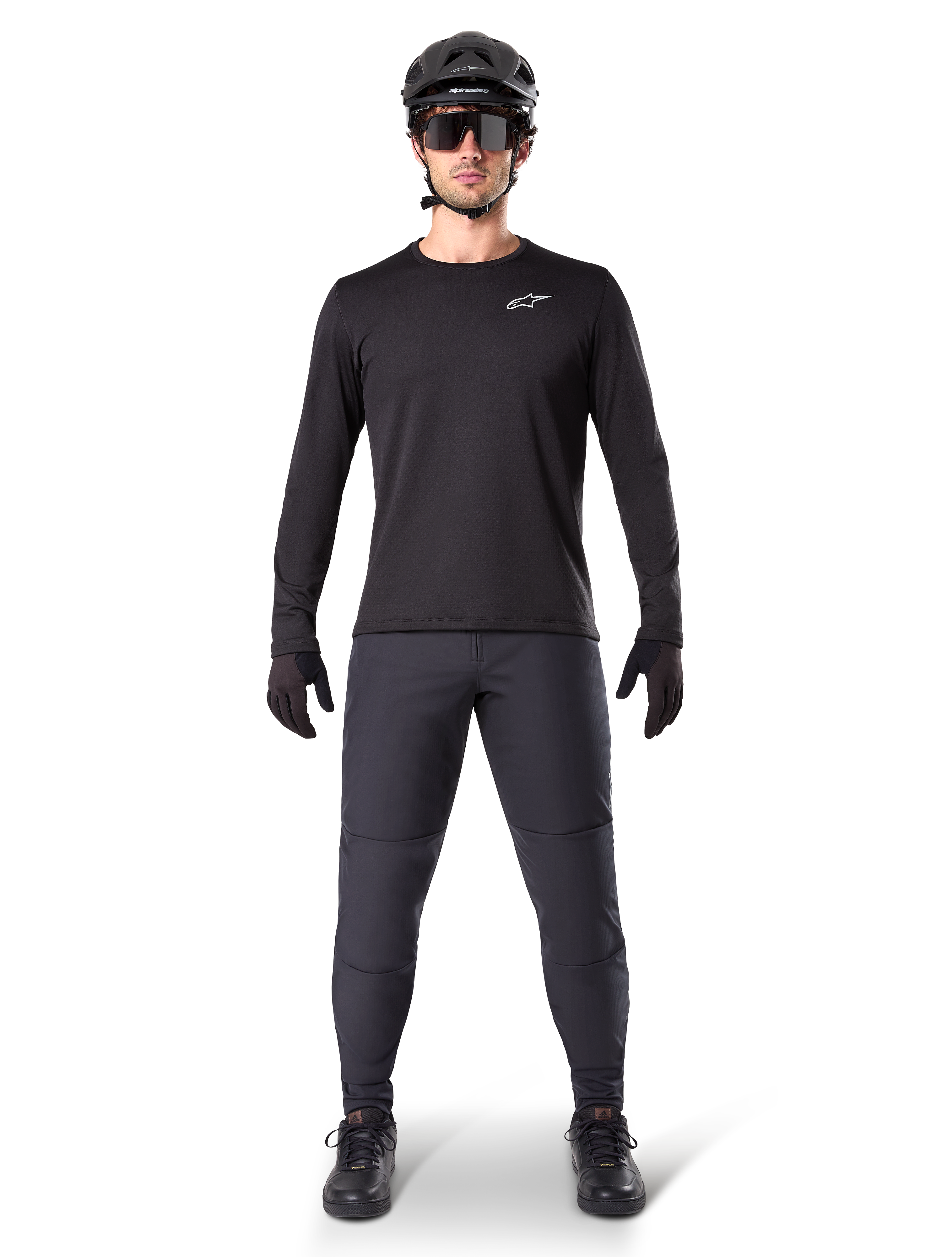 Alpinestars A-Dura Thermal Pant, zwarte MTB-broek, gedragen door een rijder in complete mountainbike-uitrusting inclusief een zwart jersey met lange mouwen, helm en zonnebril, duurzame broek met een normale pasvorm voor trailrijden in koud weer