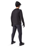 Alpinestars A-Dura Thermal Pant, mountainbike broek, zwart, achteraanzicht, gedragen met een bijpassend shirt met lange mouwen, zwarte MTB-helm en handschoenen, technische fietskleding voor koud weer