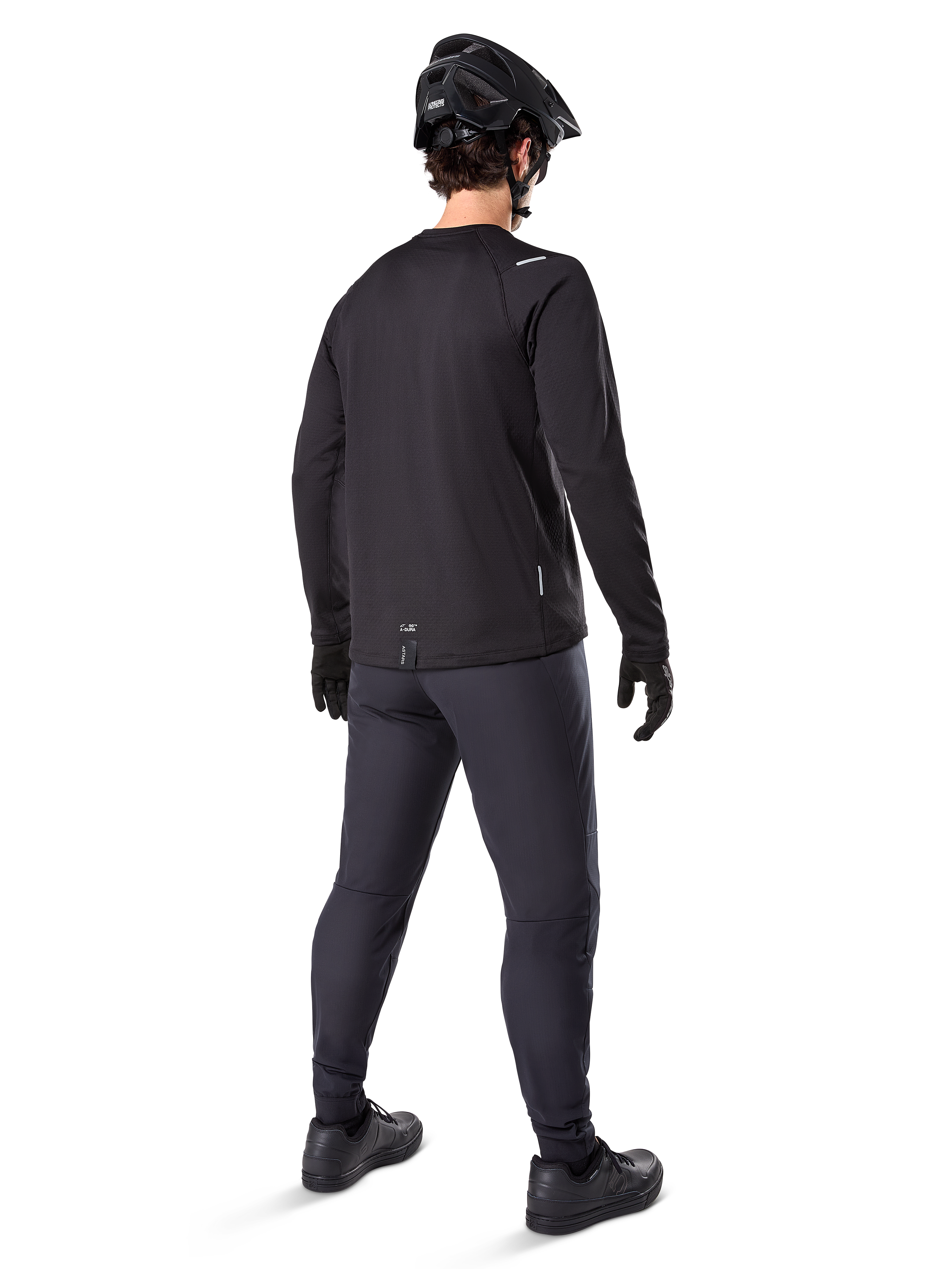 Alpinestars A-Dura Thermal Pant, mountainbike broek, zwart, achteraanzicht, gedragen met een bijpassend shirt met lange mouwen, zwarte MTB-helm en handschoenen, technische fietskleding voor koud weer