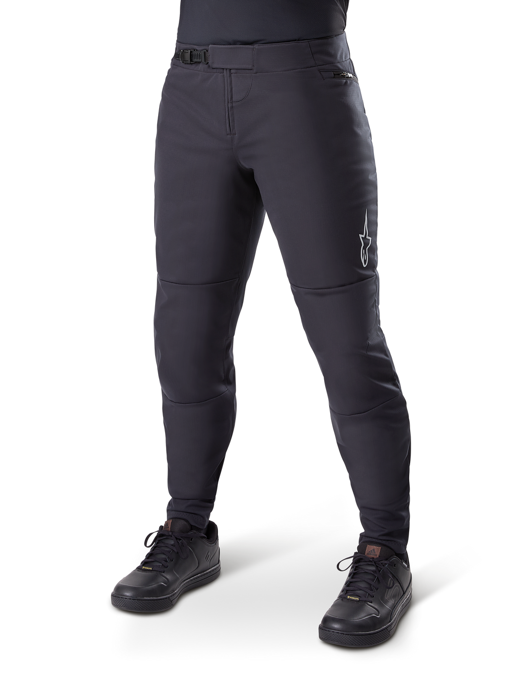 Alpinestars A-Dura Thermal Pant, zwarte mountainbikebroek, gedragen met zwarte fietsschoenen, voorzien van een ratelsluiting in de taille, klein wit logo op het bovenbeen, taps toelopende pasvorm voor koud weer