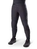 Alpinestars A-Dura Thermal Pant, zwarte mountainbikebroek, gedragen met zwarte fietsschoenen, voorzien van een ratelsluiting in de taille, klein wit logo op het bovenbeen, taps toelopende pasvorm voor koud weer