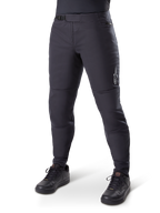 Alpinestars A-Dura Thermal Pant, zwarte mountainbikebroek, gedragen met zwarte fietsschoenen, voorzien van een ratelsluiting in de taille, klein wit logo op het bovenbeen, taps toelopende pasvorm voor koud weer