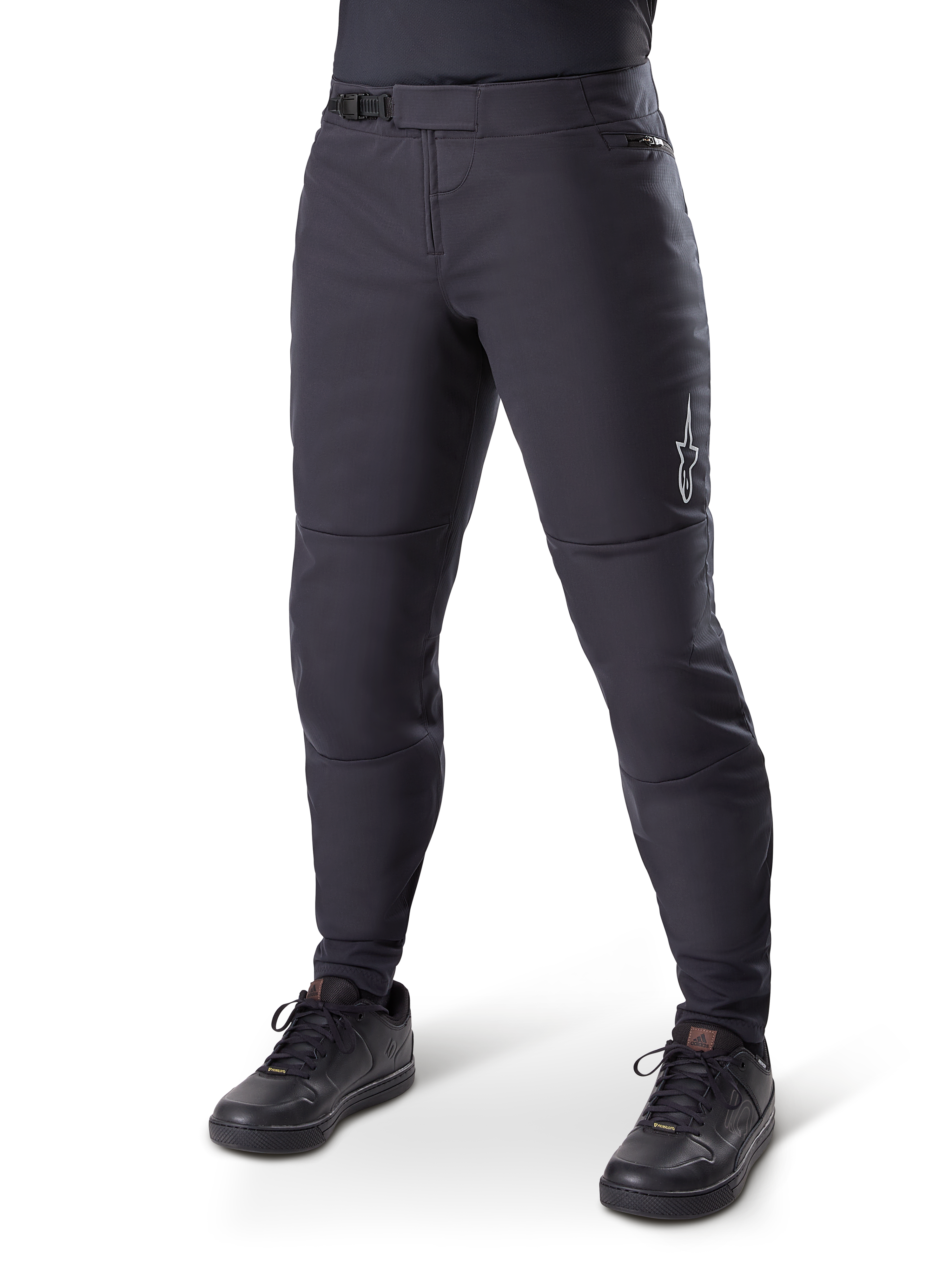 Alpinestars A-Dura Thermal Pant, zwarte mountainbikebroek, gedragen met zwarte fietsschoenen, voorzien van een ratelsluiting in de taille, klein wit logo op het bovenbeen, taps toelopende pasvorm voor koud weer