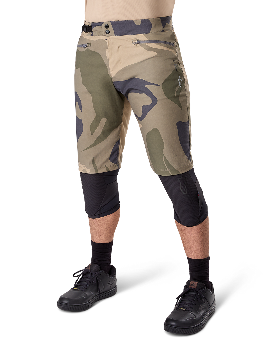 Alpinestars A-Dura Camo Liner Short, mountainbike short, bruin camouflagepatroon, vooraanzicht met ritszakken en tailleverstellers aan de zijkant, gedragen met zwarte kniebeschermers en zwarte fietsschoenen, duurzame uitrusting voor MTB