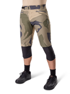 Alpinestars A-Dura Camo Liner Short, mountainbike short, bruin camouflagepatroon, vooraanzicht met ritszakken en tailleverstellers aan de zijkant, gedragen met zwarte kniebeschermers en zwarte fietsschoenen, duurzame uitrusting voor MTB