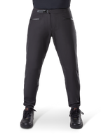 Alpinestars A-Dura Waterproof Pants, zwarte mountainbikebroek voorzien van een ratelsluiting in de taille en zakken met rits, vooraanzicht op model gedragen met zwarte schoenen, duurzame waterdichte uitrusting voor MTB