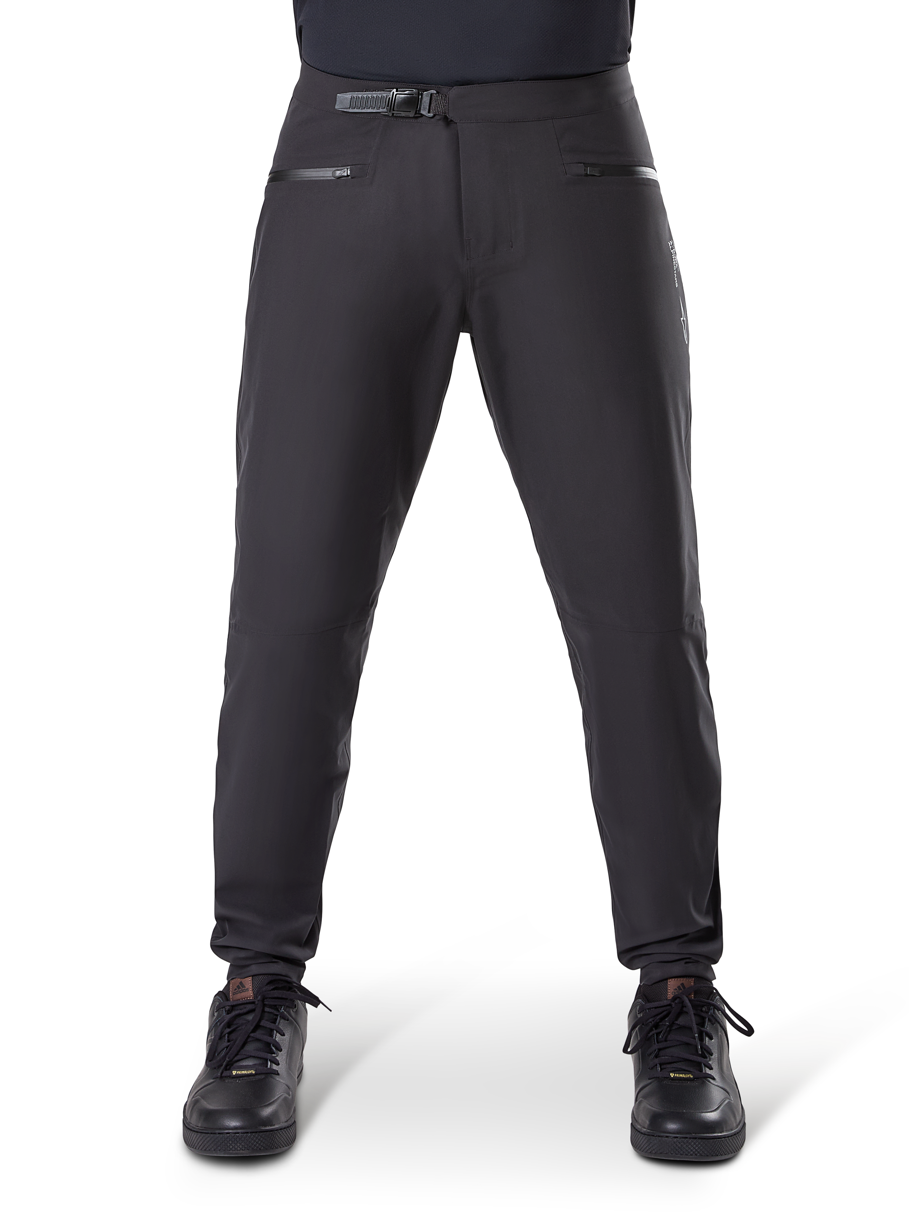 Alpinestars A-Dura Waterproof Pants, zwarte mountainbikebroek voorzien van een ratelsluiting in de taille en zakken met rits, vooraanzicht op model gedragen met zwarte schoenen, duurzame waterdichte uitrusting voor MTB