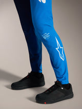 Faded Bright Blue A-Supra Elite Broek met witte Astars-branding op het onderbeen en zwarte MTB-schoenen.