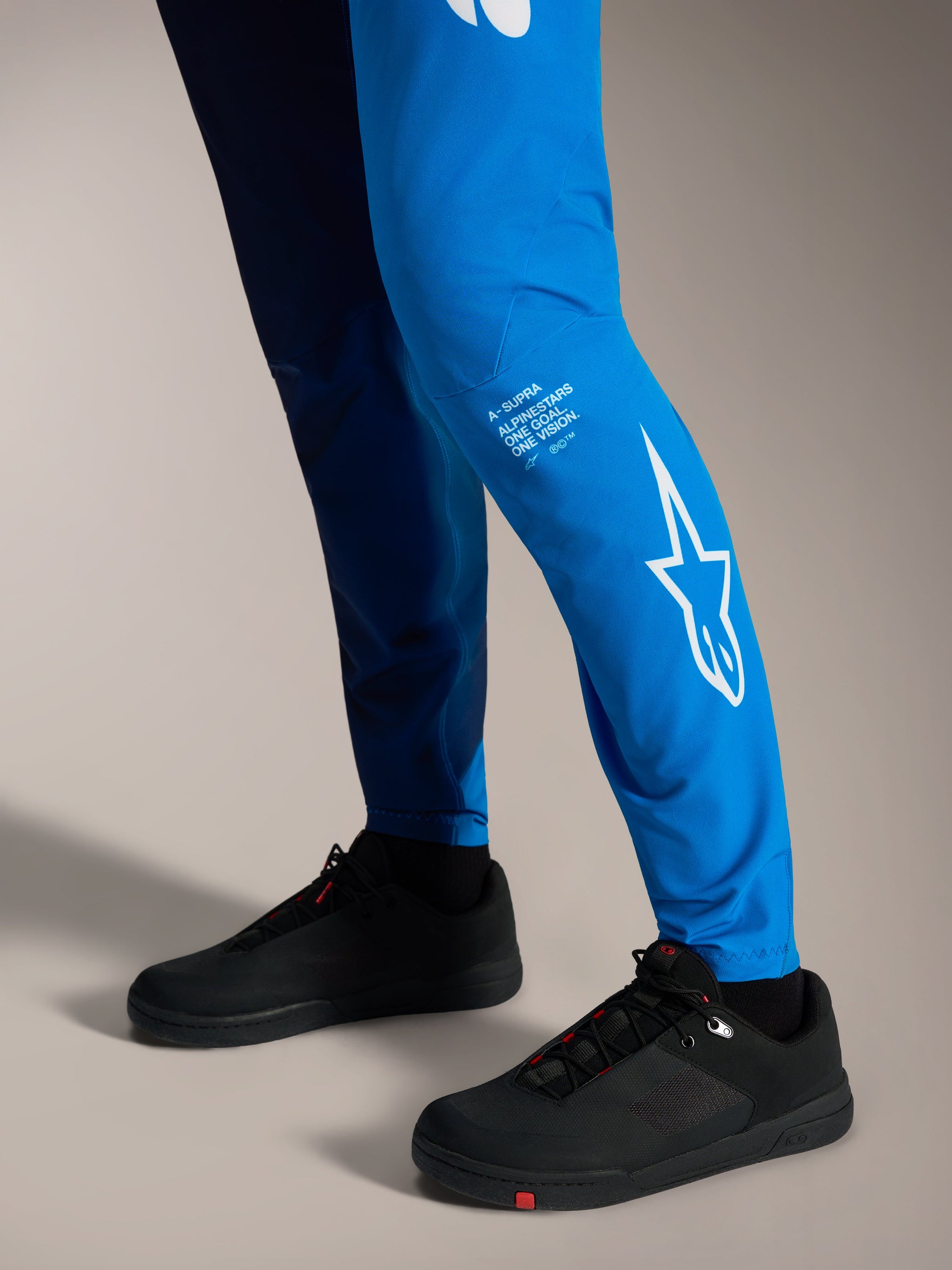 Faded Bright Blue A-Supra Elite Broek met witte Astars-branding op het onderbeen en zwarte MTB-schoenen.