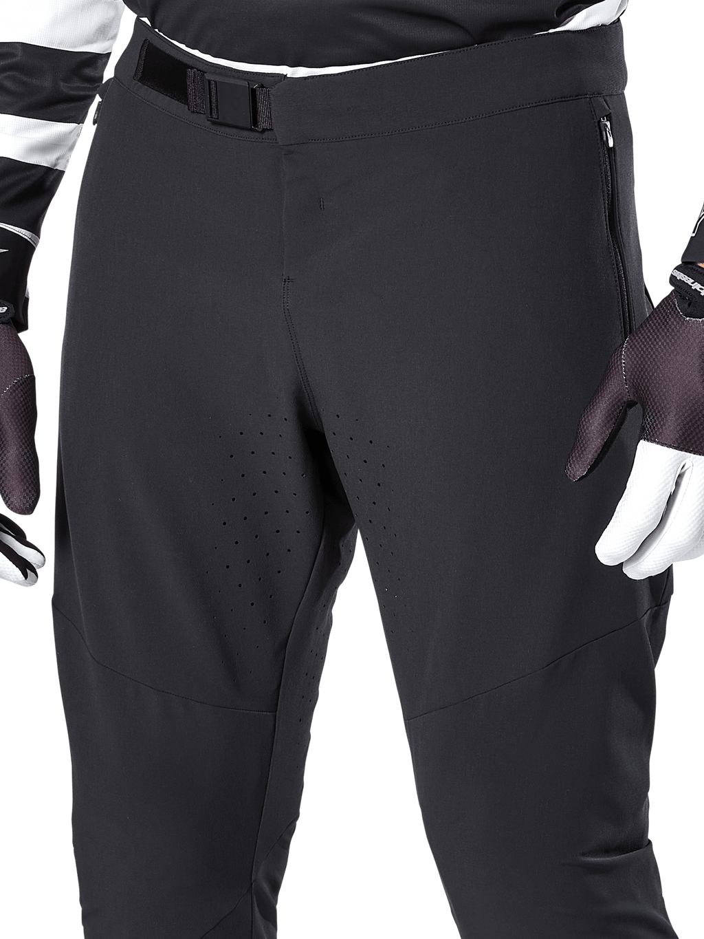 Alpinestars A-Aria Elite broek, zwarte mountainbikebroek, close-up van de voorkant van de taille en bovenbenen met magnetische gespsluiting en lasergesneden ventilatieopeningen, gecombineerd met fietshandschoenen