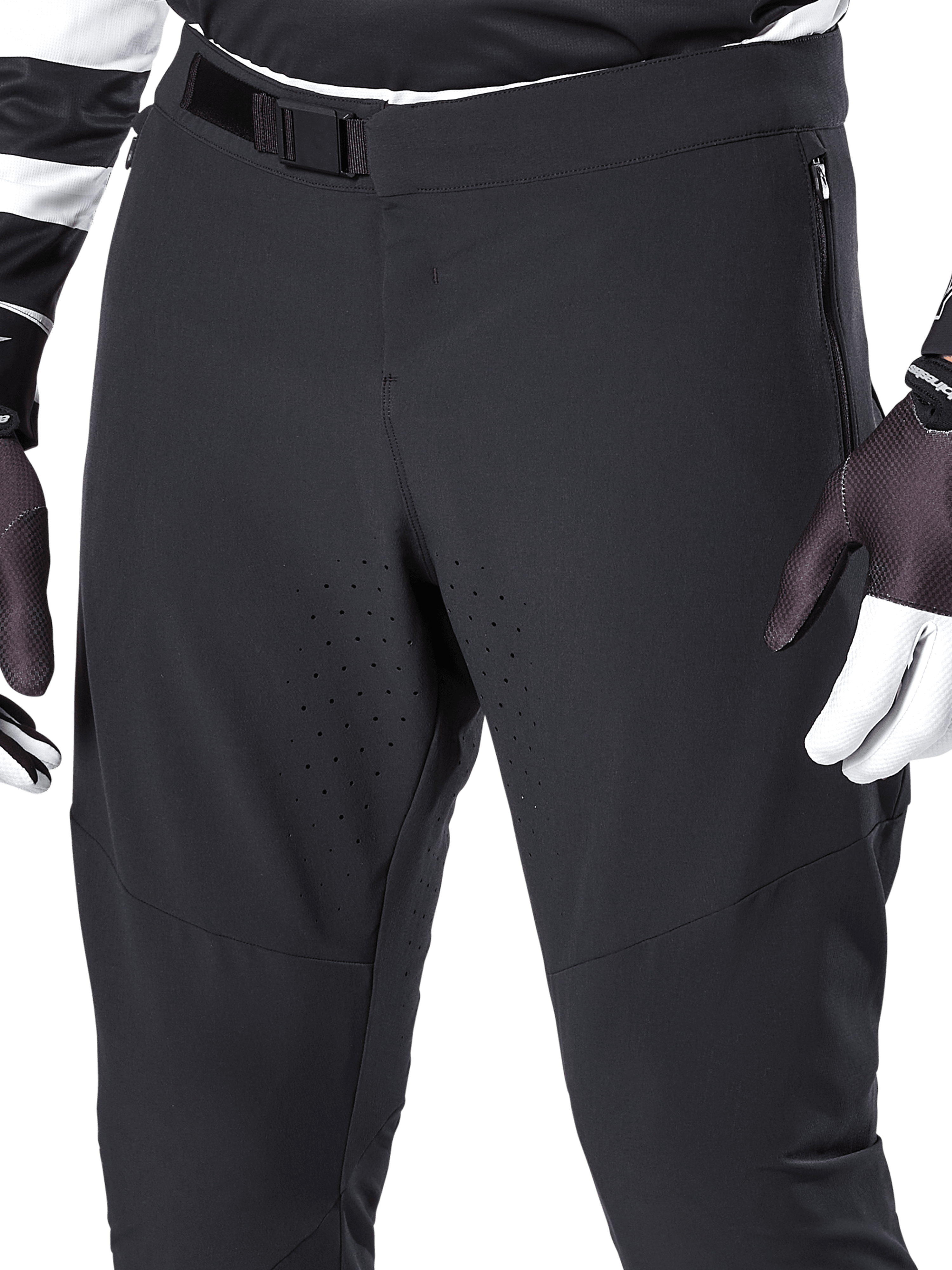 Alpinestars A-Aria Elite broek, zwarte mountainbikebroek, close-up van de voorkant van de taille en bovenbenen met magnetische gespsluiting en lasergesneden ventilatieopeningen, gecombineerd met fietshandschoenen