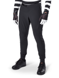 Alpinestars A-Aria Elite broek, zwarte mountainbikebroek, met lasergesneden ventilatie op de dijen en magnetische gespsluiting, gedragen met zwart-wit gestreepte jersey en handschoenen, performance MTB-kleding voor off-road fietsen