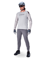 Alpinestars A-Aria Elite Pants, Dark Gray MTB Pants, worn by a rider with a light gray long-sleeve jersey and gray helmet, featuring laser-cut ventilation on the thighs and a tapered performance fit for mountain biking.