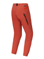 Alpinestars A-Dura Elite broek, mountainbike (MTB) broek, donkeroranje, driekwart achteraanzicht met opvallende zwarte Alpinestars-branding op de dij, feloranje ritsaccent op de heup en elastische enkelmanchetten, technische performance wielerkleding