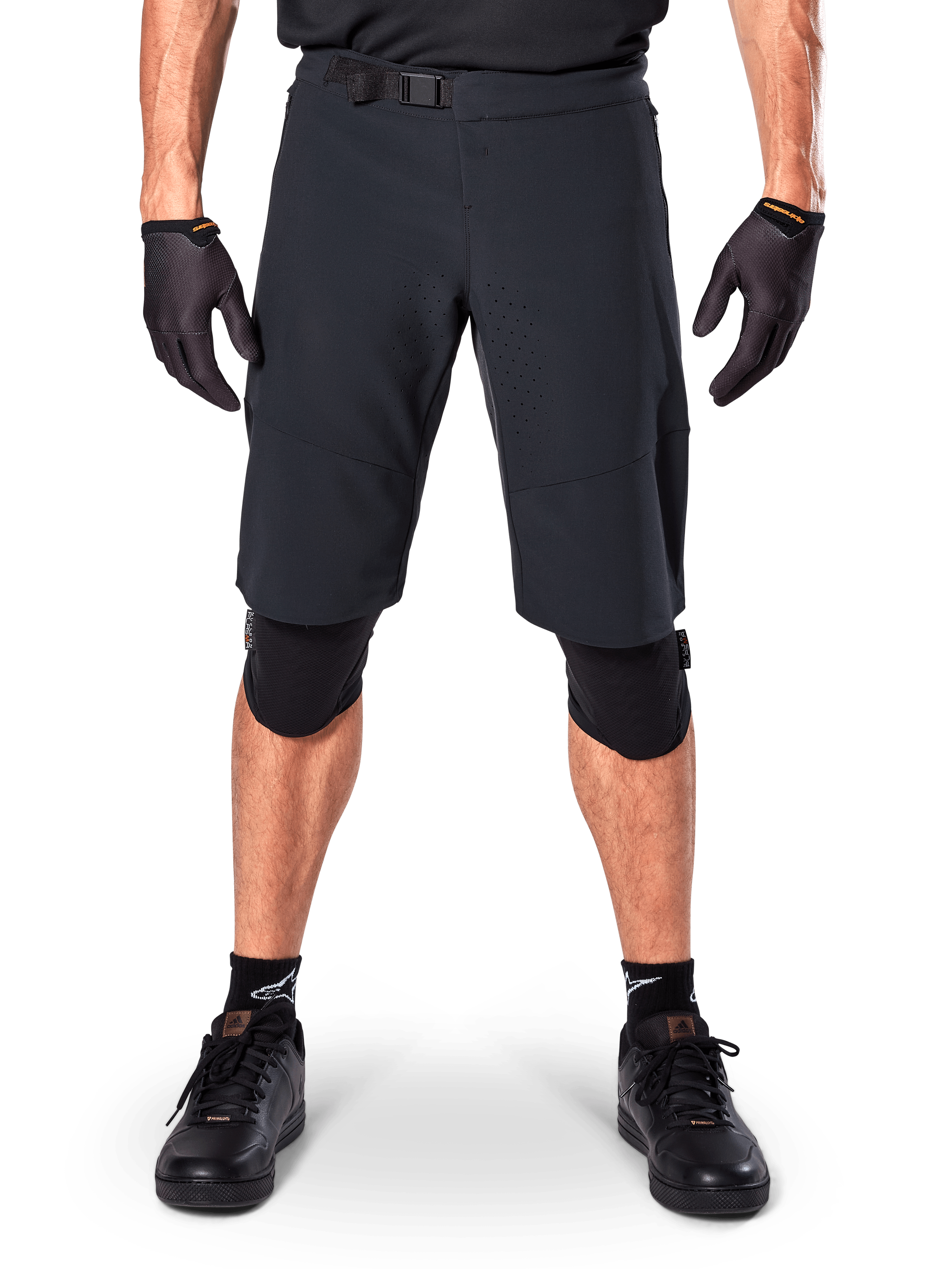 Alpinestars A-Aria Elite Shorts, mountainbike shorts, zwart, gedragen met kniebeschermers en zwarte handschoenen, voorzien van lasergesneden ventilatie en een verstelbare gesp in de taille, prestatiegerichte off-road fietskleding