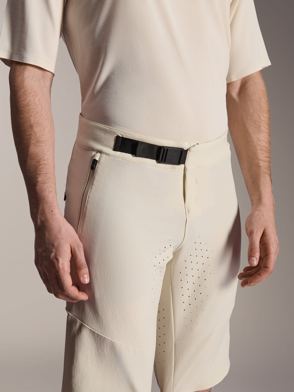 Alpinestars A-Aria Elite Shorts, mountainbike shorts, ecru, close-up van de zwarte magnetische gespsluiting, zijzak met rits en laser-gesneden ventilatie, technische fietskleding