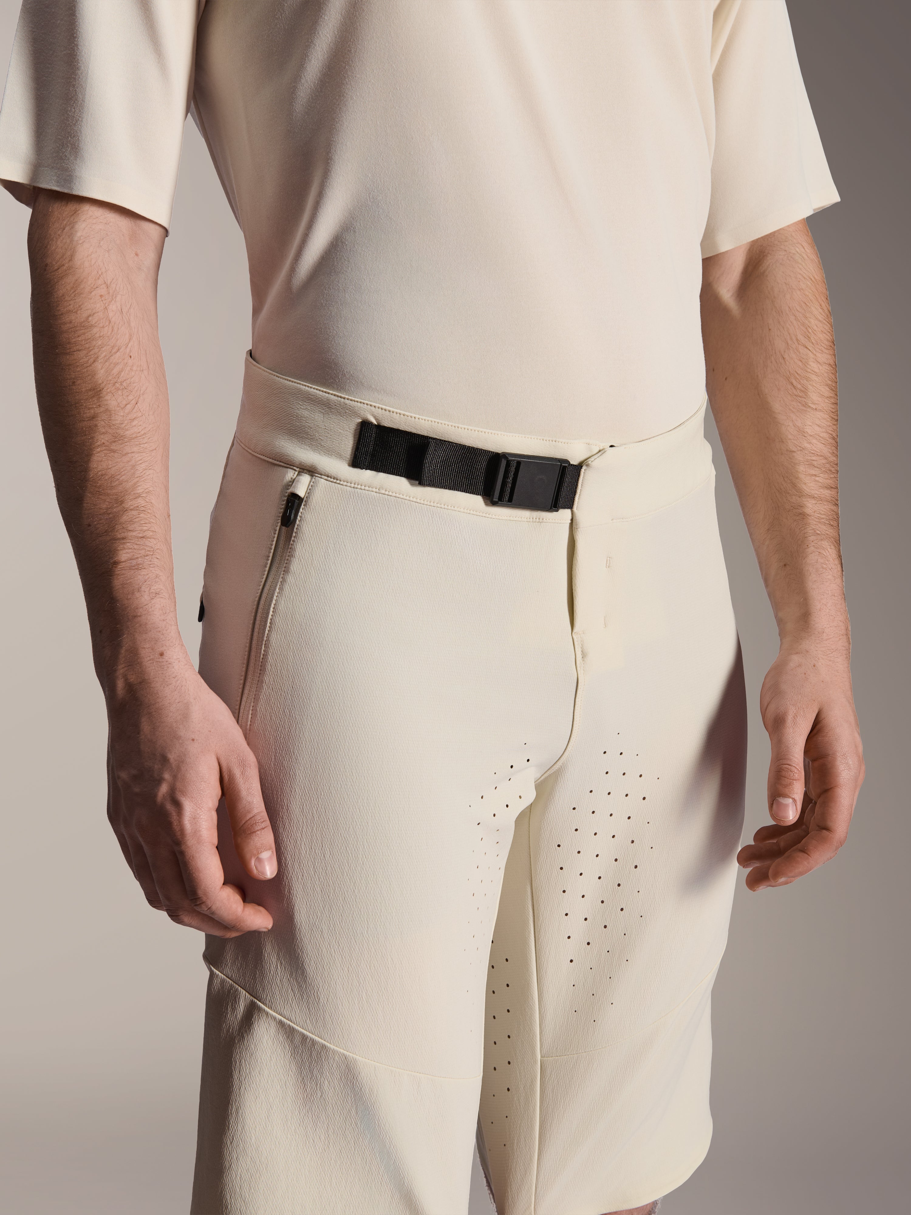 Alpinestars A-Aria Elite Shorts, mountainbike shorts, ecru, close-up van de zwarte magnetische gespsluiting, zijzak met rits en laser-gesneden ventilatie, technische fietskleding