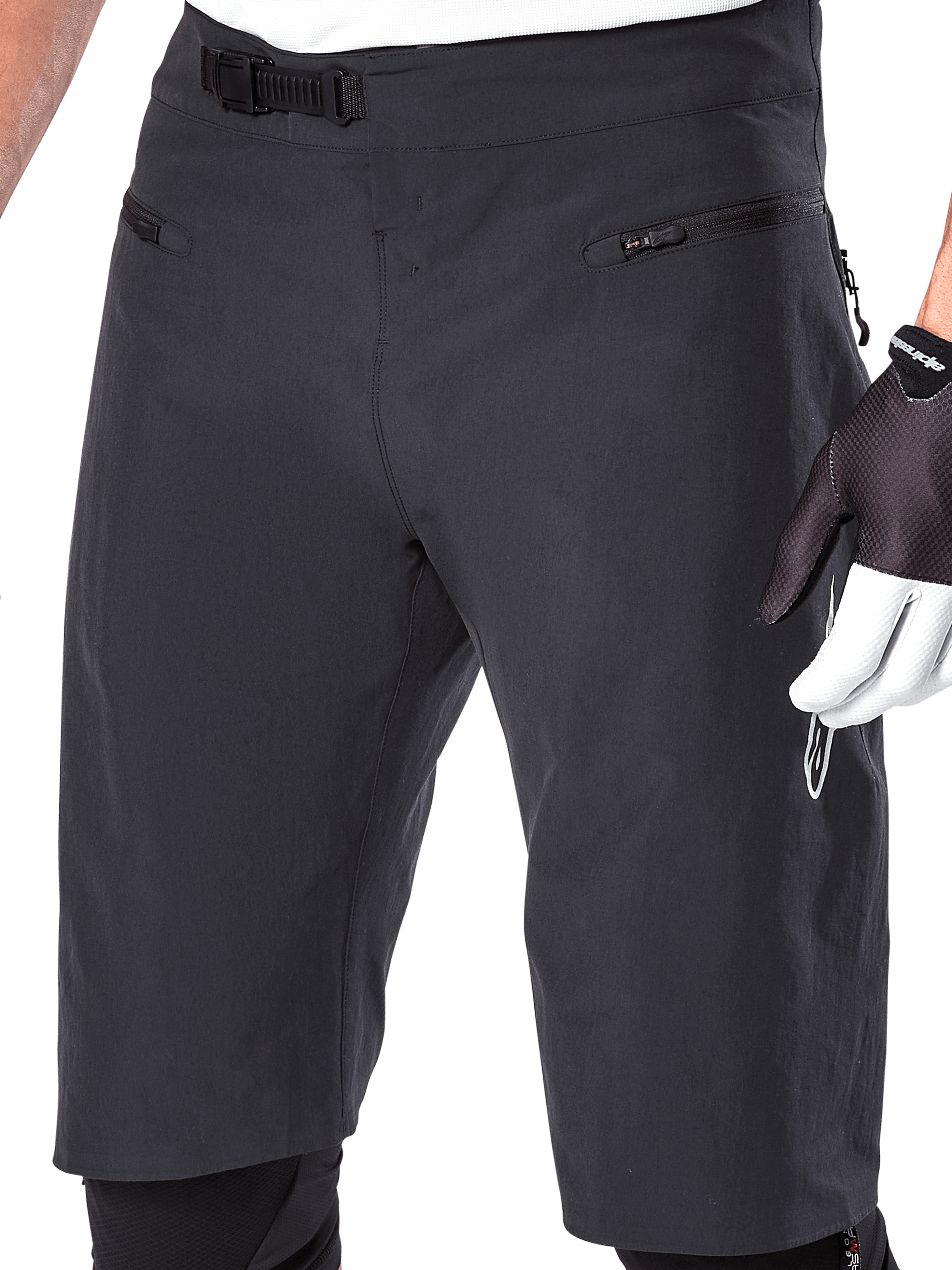 Alpinestars A-Aria Shorts, Mountain Bike Shorts, Black, close-up view of the front waist and thighs showing the ratchet closure system and zippered pockets, worn with black and white cycling gloves, performance trail gear.