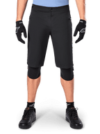 Alpinestars A-Dura Elite Shorts, zwarte mountainbike short, gedragen door een rijder met zwarte handschoenen en kniebeschermers, met drukknoopsluiting aan de voorzijde en ritszakken, duurzaam Cordura-materiaal voor off-road fietsen