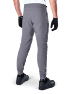Alpinestars A-Dura Pants, mountainbikebroek, donkergrijs, achteraanzicht van model die de kleding draagt, voorzien van een duurzame 2-way stretchstof en elastische boorden, gecombineerd met zwarte handschoenen en sneakers voor een complete fietslook